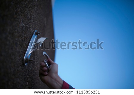 Worker clipping locking carabiner into industrial rope access fall arrest, abseiling stainless approved certified anchor point installed with expansion bolts on construction site, Sydney

