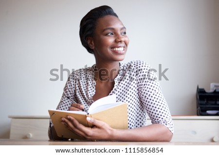 Portrait of smiling young black woman writing in journal at home Royalty-Free Stock Photo #1115856854