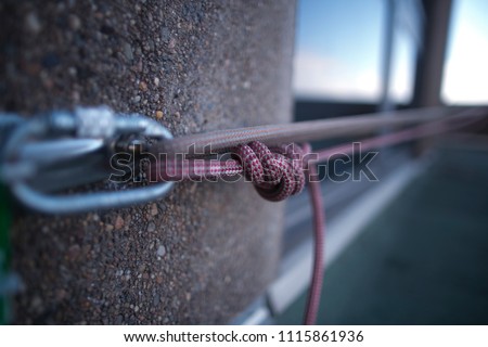 Picture side view of  industrial rope access fall arrest, abseiling stainless approve certifies anchor point and locking carabiner clipping into with figure of nine knot on roof top construction site