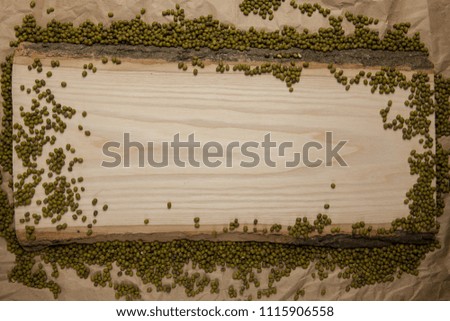 Piece of raw wood with moong dal on crumpled brown paper background. Top view, space for text.