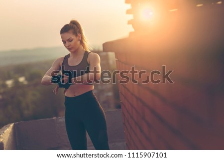 Woman wrapping hands with bandages before workout on a building rooftop terrace