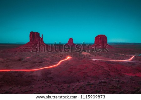 Classic panoramic view of scenic Monument Valley with the famous Mittens and Merrick Butte with light trails at night in summer, Arizona, American Southwest, USA