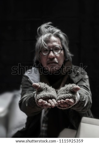 Old man white long hair beggar homeless wears dirty knitting gloves hands up to beg some money donation. Focus shooting at hands.