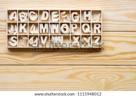 Capital wooden block letter A-Z alphabet set in wooden box isolated on wooden background.