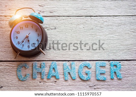 Retro clock and CHANGER word made with wooden alphabets over wooden background. Selective focus