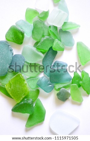 Sea glass pieces isolated on white. Green pieces of glass polished by the sea closeup background. A pile of natural beach glass. Multi-colored pieces of polished glass. 