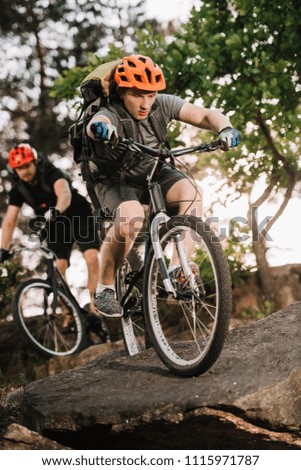 active young trial bikers riding on rocks at pine forest