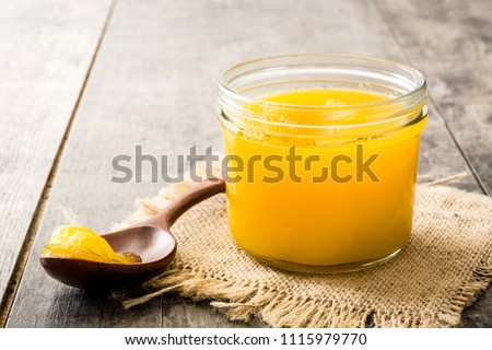 Ghee or clarified butter in jar and wooden spoon on wooden table.  Royalty-Free Stock Photo #1115979770