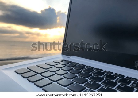 Close up shot of keypad and screen of white laptop with bright sunset or sunrise cloudy sky on background. Copy space on black monitor for your text, logo or picture.