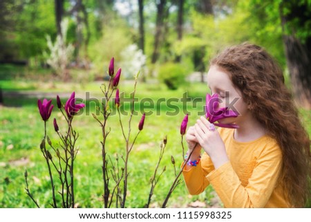 girl in yellow smelling magnolia