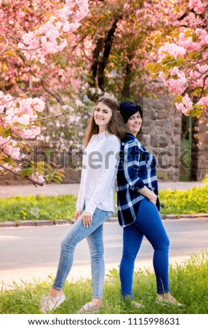Mother with an adult daughter together in a blooming sakura park