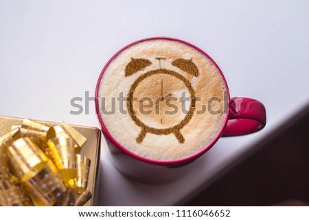 cup of cappuccino with pattern of cinnamon clock on milk foam
