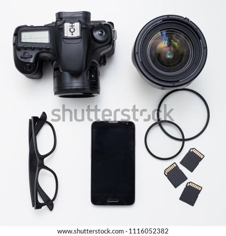 photographer's equipment - top view of camera, lenses, cards and smart phone over white table background