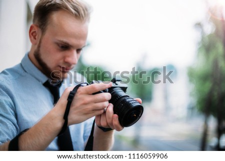 young man photographer shoots a mirrorless camera and fisheye lens. A tourist with a camera in the city and nature.