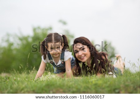 Mom and daughter on the grass in the park, woman and child in nature 