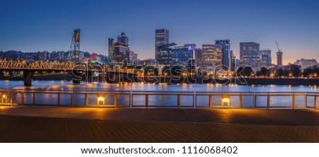 Beautiful Panorama of Downtown Portland  cityscape skyscrapers and Hawthorne Bridge during late sunset/early night with glowing yellow lights and dark blue night sky, in Portland, Oregon, USA