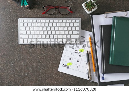 Calendar with to-do list, computer keyboard and notebooks on grey background