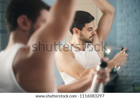 Young hispanic people and male beauty. Confident metrosexual man using spray deodorant on underarm skin, smiling and looking at mirror. Royalty-Free Stock Photo #1116083297