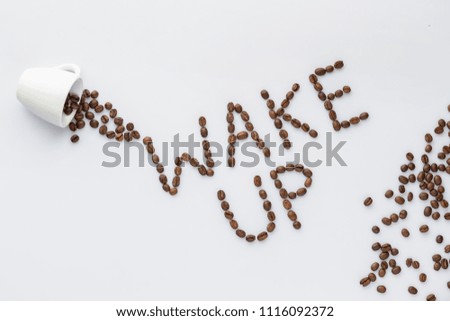 Roasted coffee beans make wake up letters on grey background