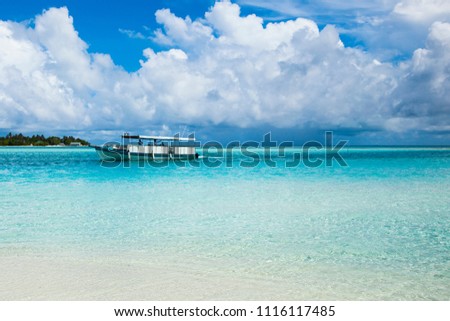 Ocean nirvana. Blue sky and clouds. Boat in blue water. Sandy shore. Maldives Island. Maldive. Summer. May.