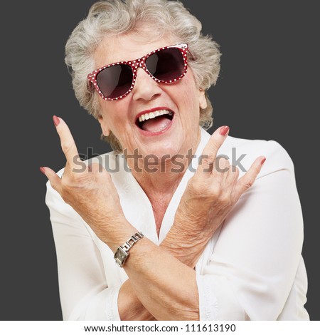 Senior woman wearing sunglasses doing funky action isolated on black background