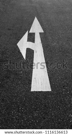 Arrow straight and turn left sign on the road.