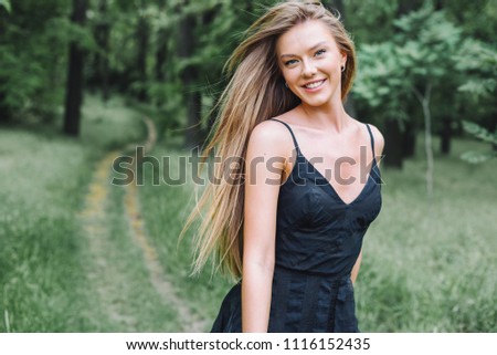 Young beautiful woman in black dress in park