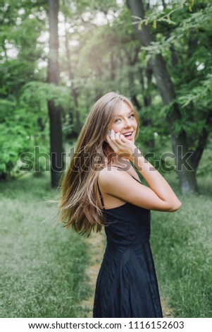 Young beautiful woman in black dress in park
