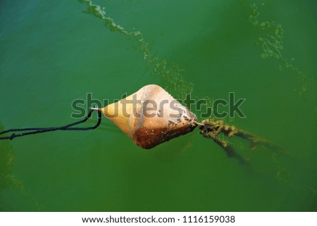float from the anchor of a yacht in the green water of the harbor