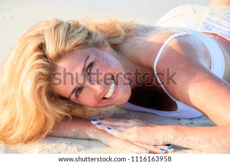 Beautiful blond woman is lying happily on the sandy beach
