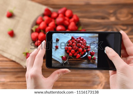 Girl takes photos on a strawberry smartphone