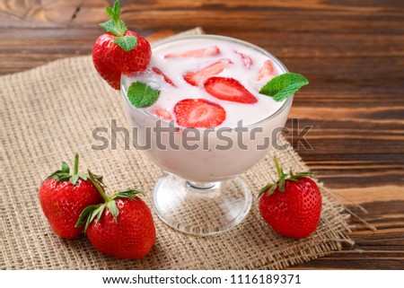 Homemade yogurt with fresh red strawberry on a wooden background. Top view.