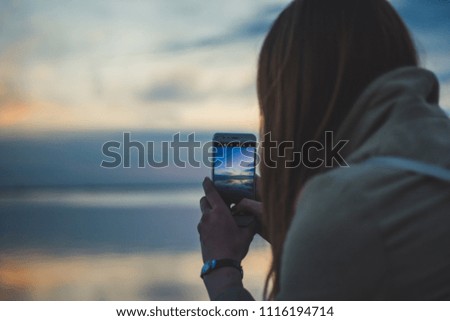 Girl taking photo of a sunset with smart phone