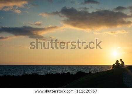 Silhouette of a couple at the ocean on a Bluff of Lava Rock above the ocean