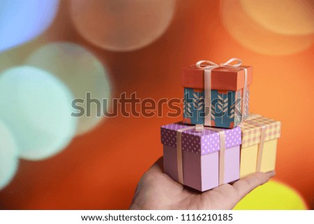 handmade gift box against orange bokeh background. gift for you. Copy space for greeting text. minimal colored box on hand. paper craft. 