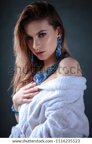 Young woman in a bathrobe and wet hair, fashion blue hand made jewelry, spa and care portrait, clean natural face, portrait on a background isolated