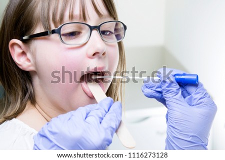 Young male laryngologist doctor using tongue depressor and swab to collect culture sample from child patient throat Royalty-Free Stock Photo #1116273128