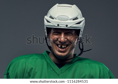 Close-up portrait of a professional hockey player in a protective sportswear and helmet on a gray background.
