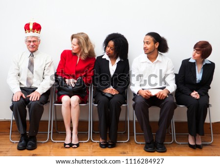 A group of prospective employees waiting for an interview. One man wears a crown to stand out from the rest. Humorous business concept.