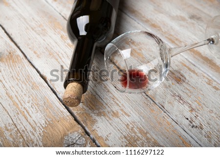 Bottle of red wine with a corkscrew. On a black wooden background.