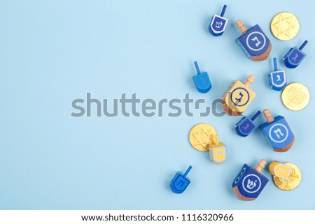 Blue background with multicolor dreidels and chocolate coins. Hanukkah and judaic holiday concept. Horizontal