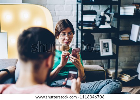 Addicted young people from social networks ignoring live communication and blogging on modern smartphones using 4G internet.Positive hipster girl in eyewear chatting on cellular in apartment