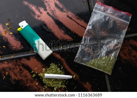 narcotic cigarette, lighter and a package of weeds on the table, short focus, toning