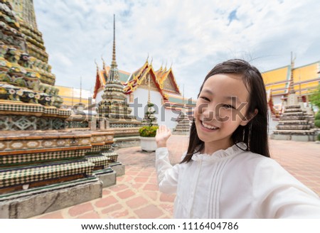 Cute happy smiling tourist girl taking self-portrait picture at Wat Phra Chetuphon or Wat Pho is a Buddhist temple in the city of Bangkok,Thailand, holiday summer vacation,travel concept.