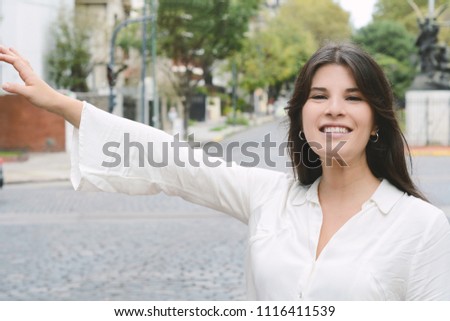 Young woman raising her arm to catch a taxi on city. Urban life and transportation concept.