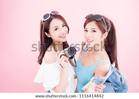 two travel woman take camera and smile happily on the pink background