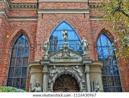 Architectural details of a beautiful church with sculptures, arch windows and a sign above the door in Latin ‘The word of God remains forever’. Sweden, Stockholm 