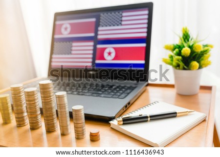 USA vs Korea flag in Laptop background with front gold silver coins and notebook with pen.