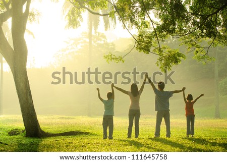 an asian family jumping in joy in the park during a beautiful sunrise, backlight