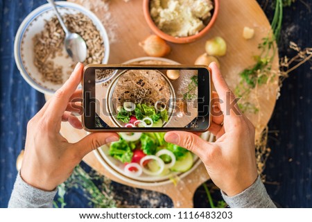 Smartphone photo of food. Woman hands make phone photography of Indian traditional bread. Garlic naan with vegetables for lunch or dinner. For social media, blogging. Raw vegan vegetarian healthy food Royalty-Free Stock Photo #1116483203